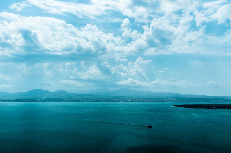 A serene aerial view of Lake Sevan with mountains and dramatic clouds in Gegharkunik Province, Armenia.