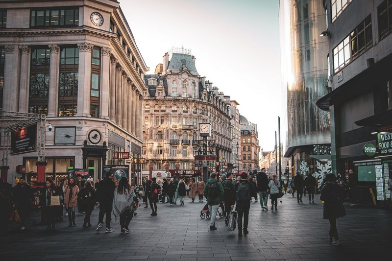 A vibrant street in London with pedestrians and historic architecture during the day.