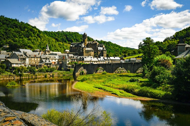 Explore the picturesque village of Estaing and its historic castle surrounded by lush greenery and a serene river.