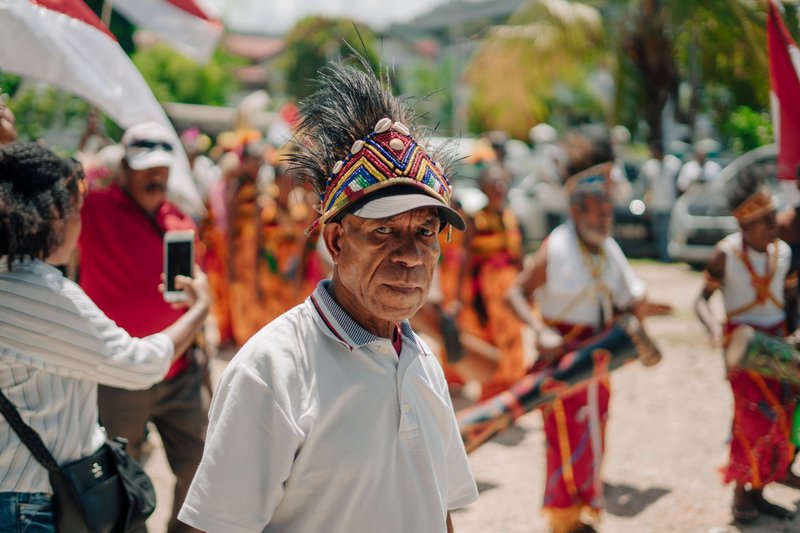 Man in traditional attire with vibrant headdress in festive cultural parade.
