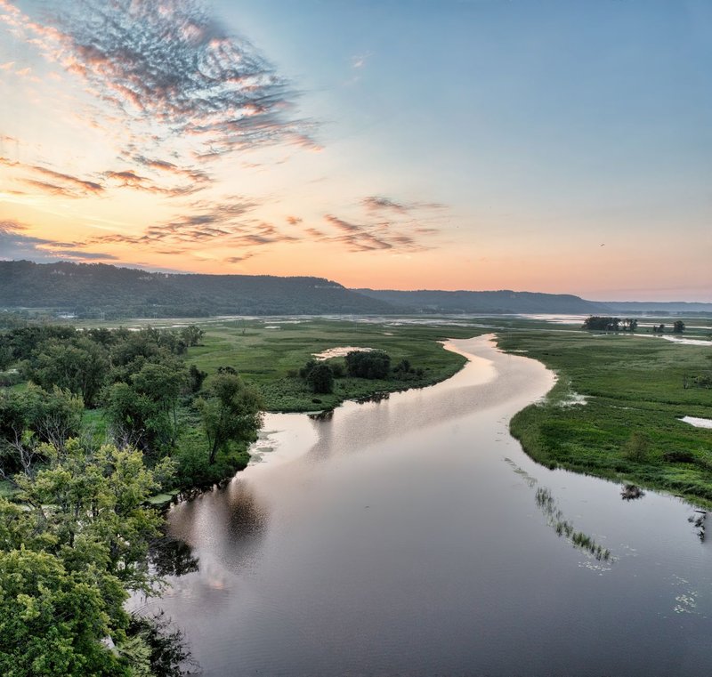 A breathtaking aerial view of the Mississippi River at sunset in Nelson, WI, showcasing lush greenery and serene waters.