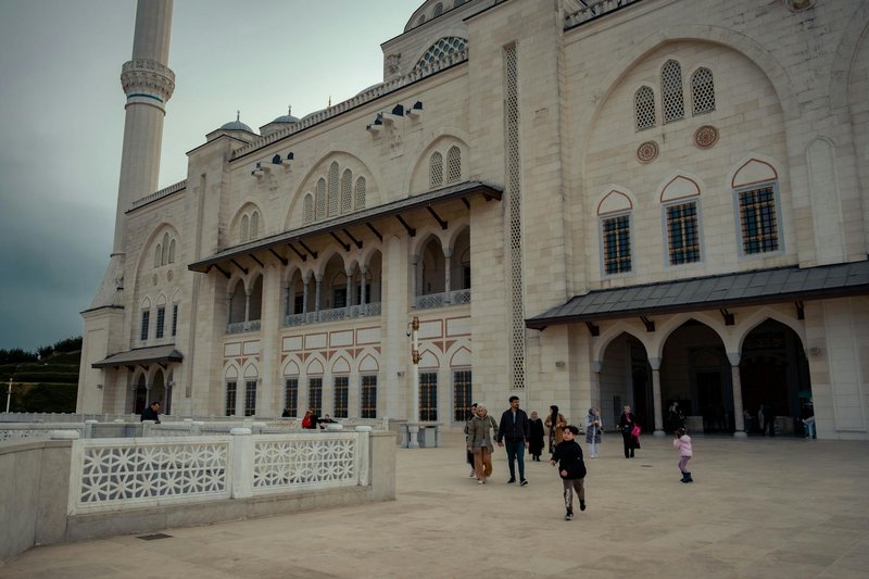 Grand Camlica Mosque's stunning facade with visitors in urban Istanbul, Turkey.