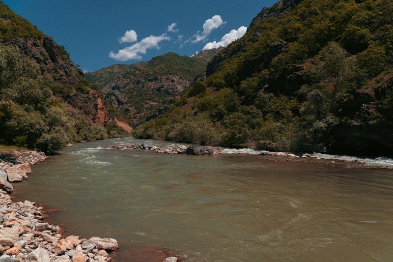 A scenic view of a river surrounded by lush green mountains in Tunceli, Türkiye.