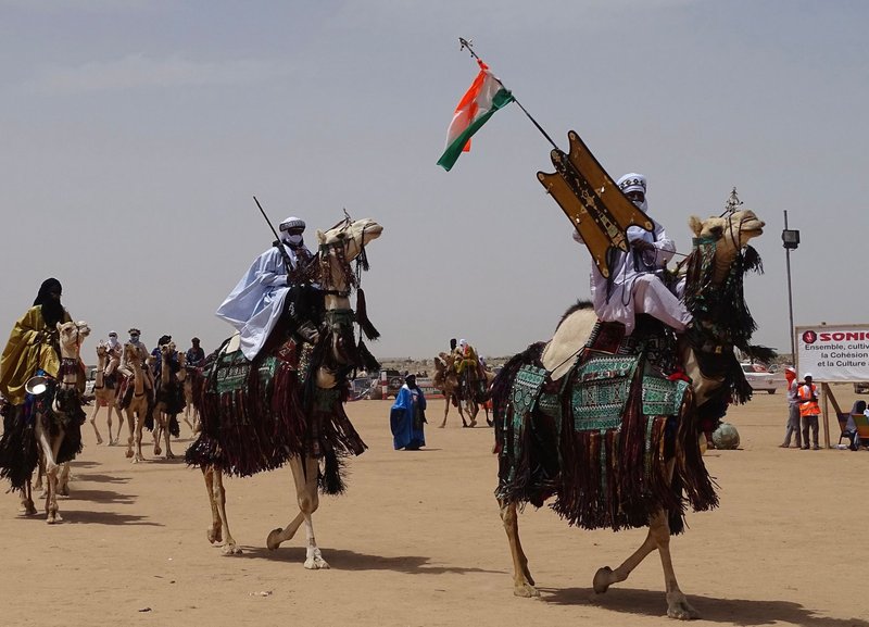 Camels and people in traditional attire at a desert festival in Ingall, Niger.