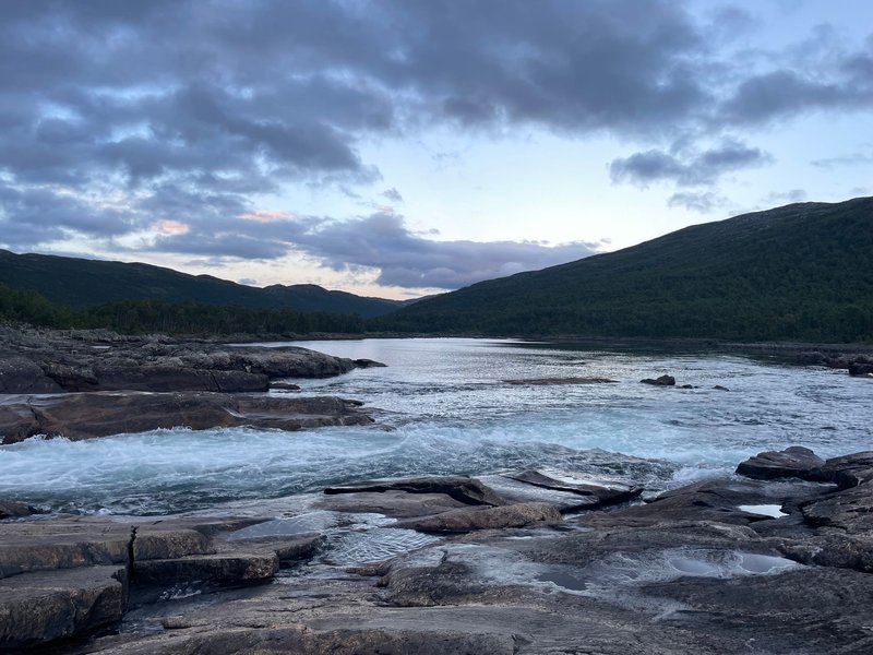 Peaceful landscape of a river flowing through rocky terrain and mountains at dawn in Norway.