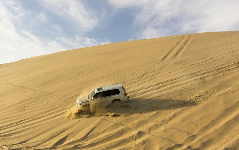 A rugged SUV tackling the sand dunes in Qatar, showcasing thrilling off-road adventure.