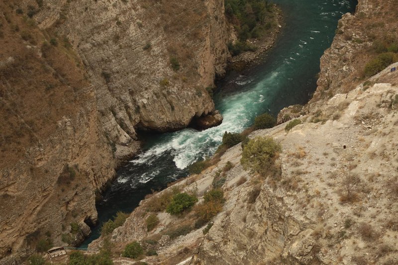 A breathtaking aerial view capturing a teal river flowing through rocky cliffs, showcasing nature's raw beauty.