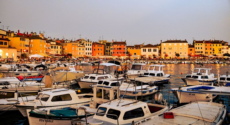 Picturesque view of Rovinj harbor with colorful buildings and boats at sunset.