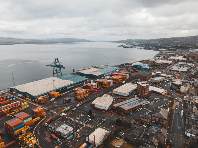 Drone shot of Greenock Harbor, Scotland, showcasing shipping infrastructure by the coast.