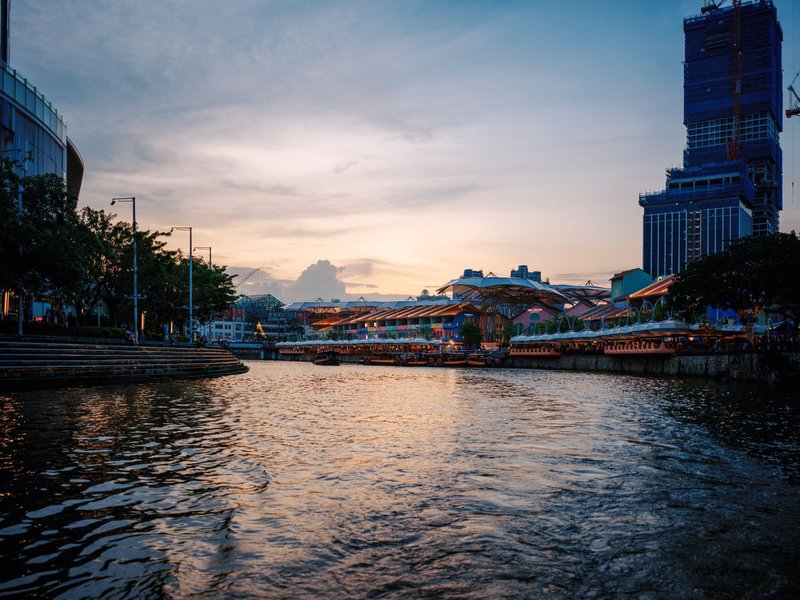 Serene view of Singapore River at sunset with skyline and riverside buildings.