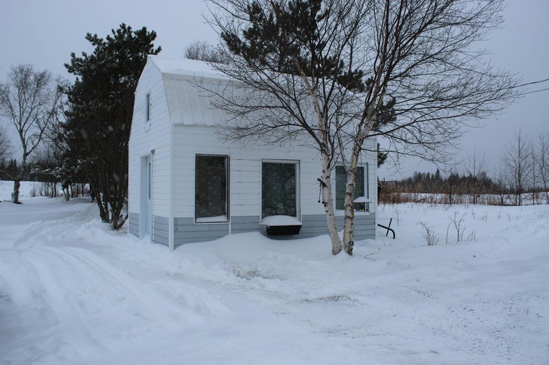 A small house surrounded by snow in a quiet rural winter setting.