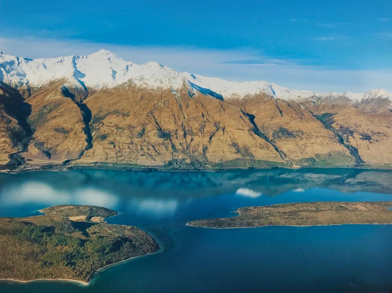 Scenic aerial shot of Lake Wakatipu with surrounding snow-capped mountains in Southland, New Zealand.