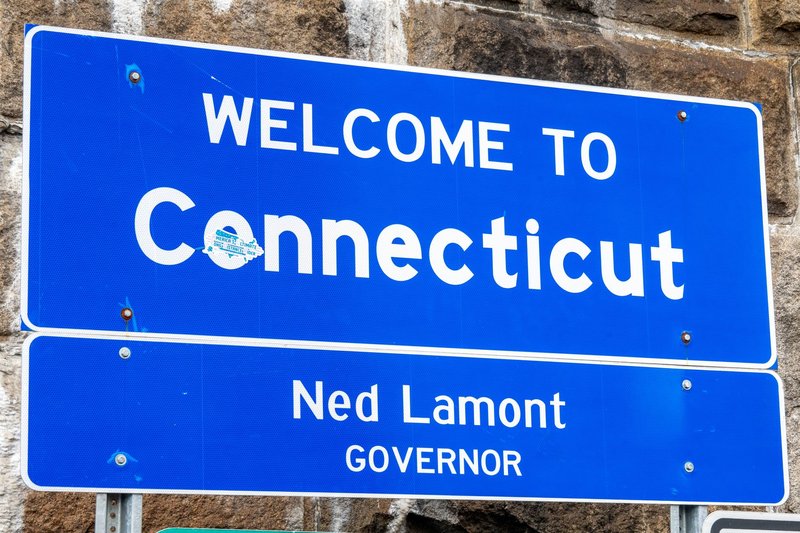 Close-up of a 'Welcome to Connecticut' sign with governor's name displayed, symbolizing state entrance.