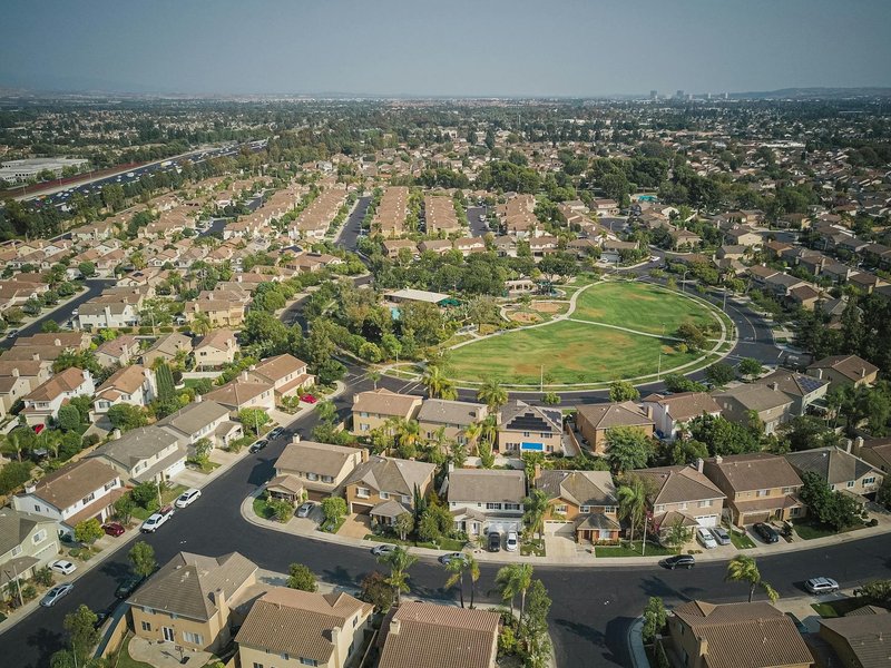 Drone shot of a spacious suburban neighborhood featuring a central park with numerous houses.
