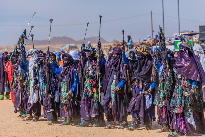 Tuareg people in vibrant traditional garb celebrating at a desert festival.