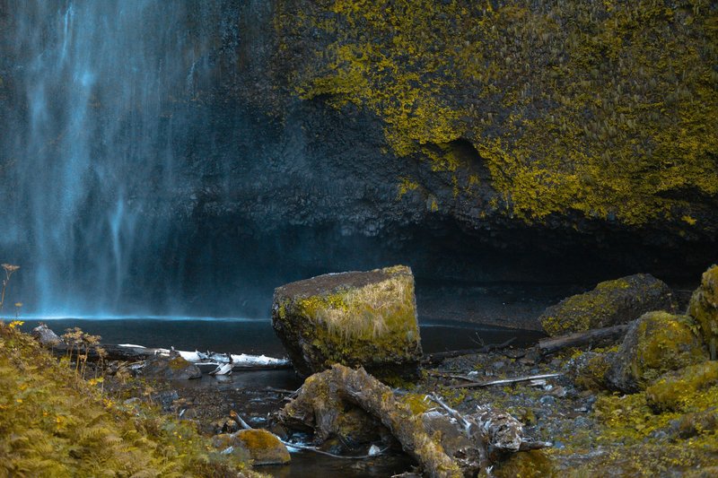Serene waterfall cascading over moss-covered rocks in a tranquil outdoor setting.