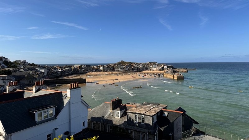 A picturesque view of St Ives beach and harbor with charming coastal townhouses.