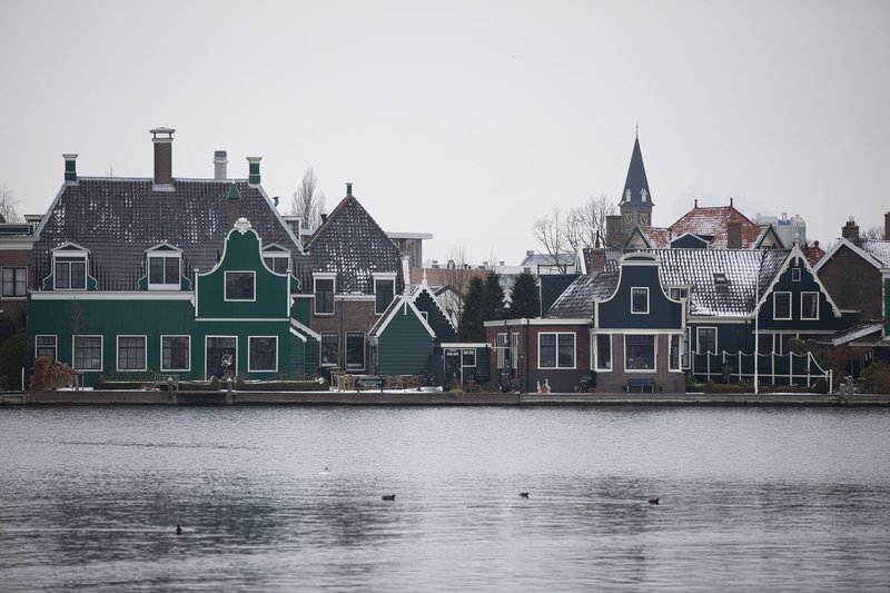Charming Dutch village with traditional architecture reflected on a wintery riverbank.