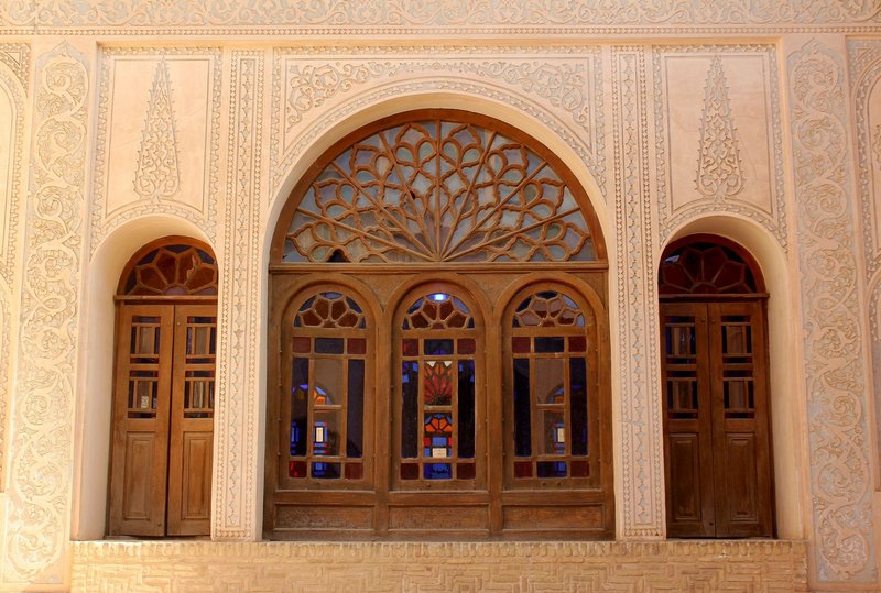 A detailed view of Persian architecture showcasing ornate wooden arched windows with intricate carvings.