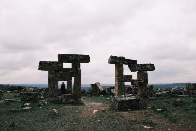Explore ancient stone ruins under a dramatic cloudy sky, capturing a sense of history.