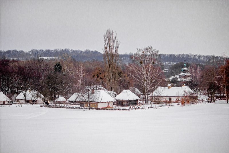 Idyllic winter scene of a snow-covered Ukrainian village with traditional architecture.