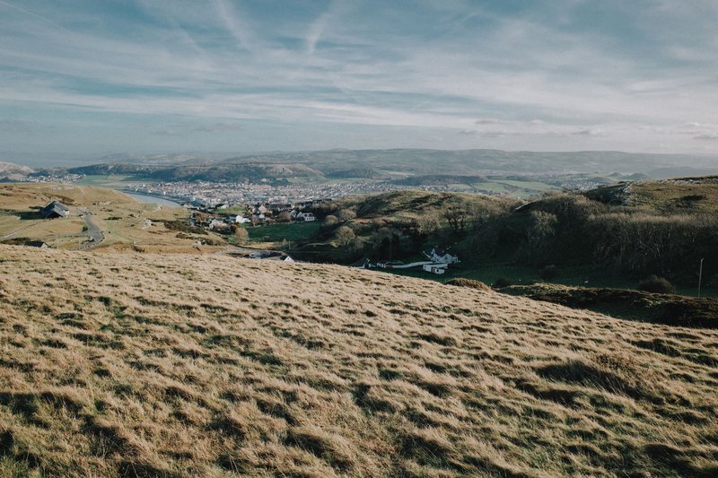 A breathtaking view of the rolling hills and a picturesque town in Wales under a clear sky.