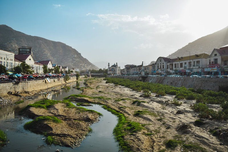 Scenic view of Kabul, Afghanistan featuring a dry riverbed and urban buildings.