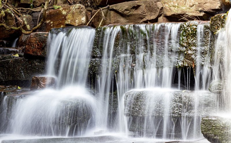 A serene long exposure of a natural waterfall cascading over rocks in Durban, South Africa.