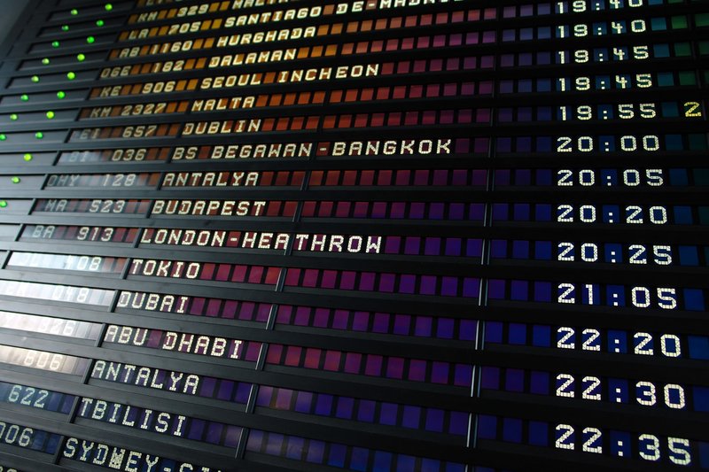 Retro flip-style airport departure board showing international flight destinations and times.