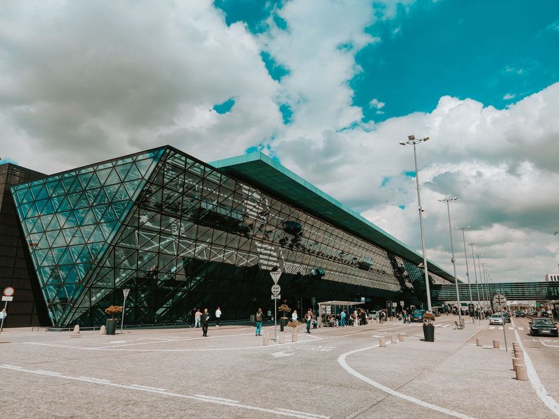 Contemporary airport terminal featuring striking glass facade under a cloudy sky.