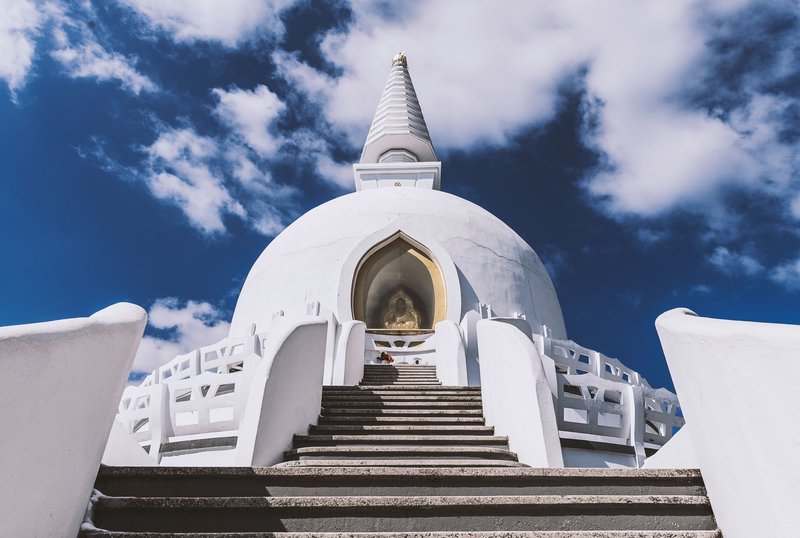 A peaceful stupa with traditional architecture set against a vibrant blue sky, symbolizing spirituality and serenity.