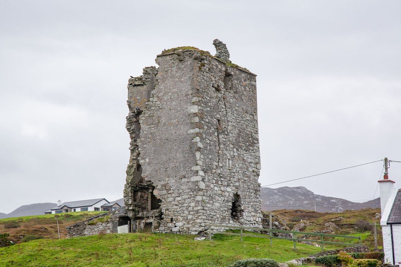 A historic stone tower ruin standing alone in a rural countryside landscape.
