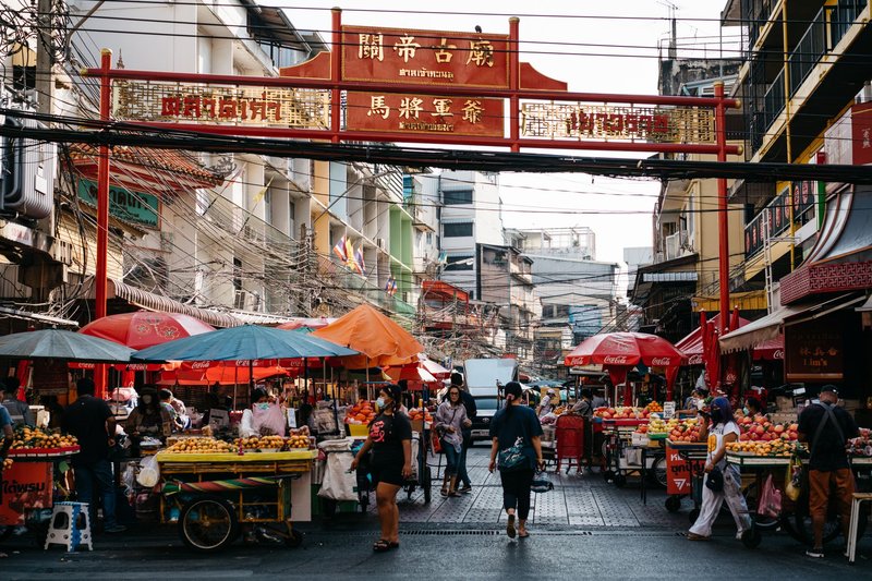 Lively scene at an Asian street market in Chinatown with bustling activity and colorful produce.