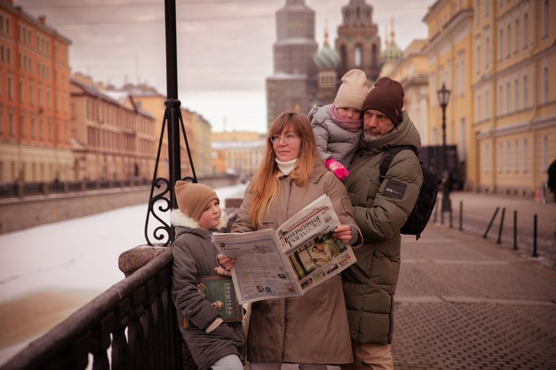 A family strolls along a canal in Saint Petersburg on a winter day, bundled up warmly against the cold.