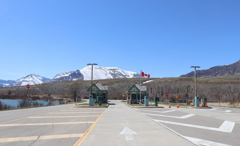 Canadian border crossing amidst stunning snow-capped mountains and clear blue sky.