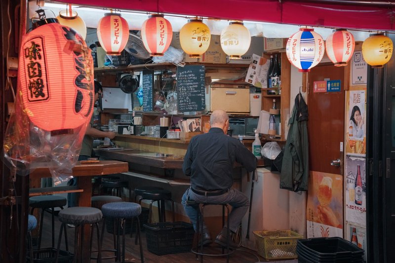 Cozy Tokyo izakaya with traditional lanterns and a customer enjoying a meal.