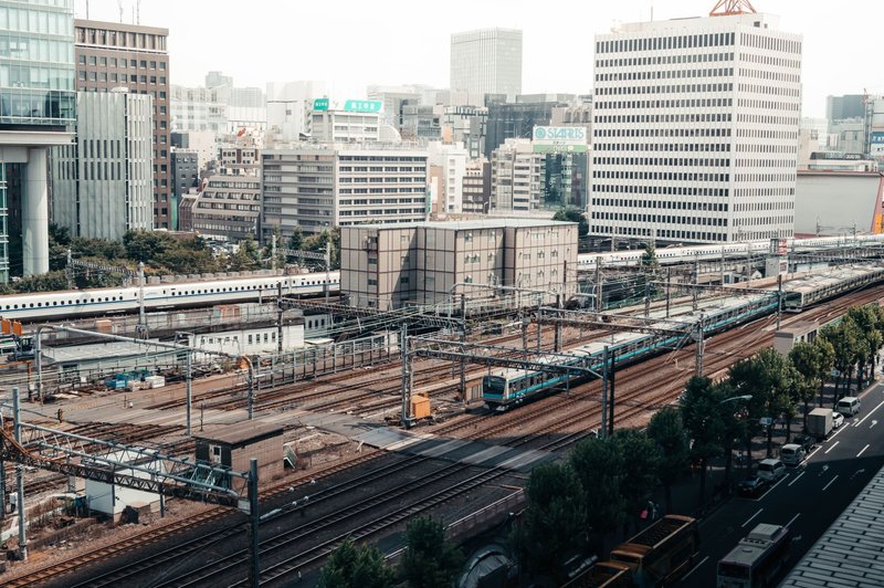 A bustling train station in Tokyo with city skyscrapers in the background.