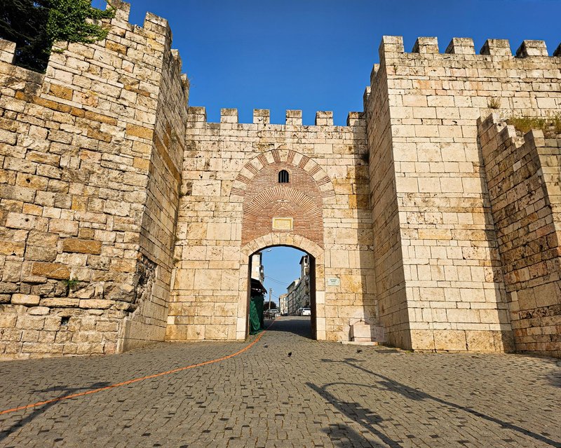 Explore the ancient stone gate leading into a historic city, showcasing classic architecture.