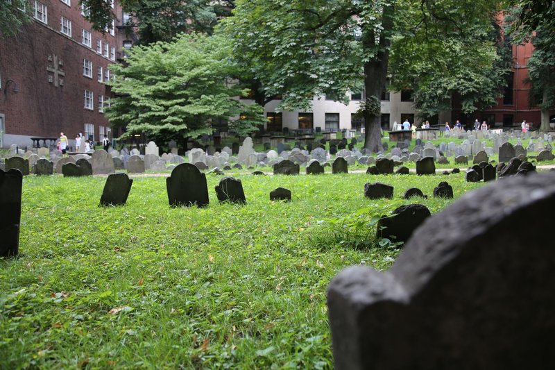 Explore the historic cemetery in Boston with ancient tombstones and lush green surroundings.