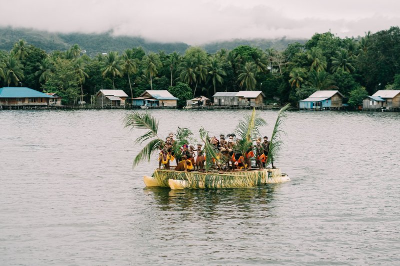 A group of people aboard a traditional boat on a serene lake in Papua, Indonesia.
