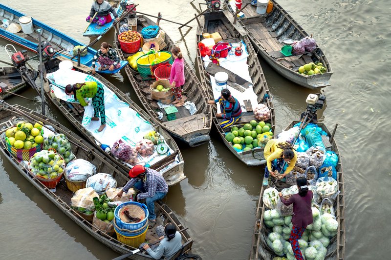 Colorful scene at an Asian floating market with boats filled with fresh fruits and vegetables.
