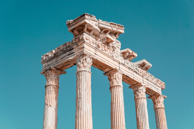 View of the historic columns of the Temple of Apollo under a clear blue sky in Antalya.