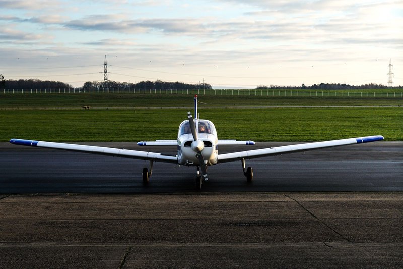 A small propeller airplane parked on an outdoor runway at sunset.