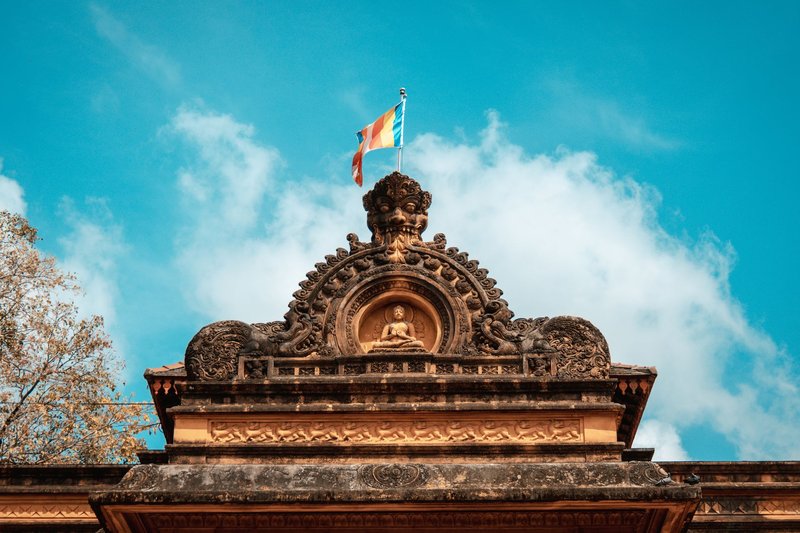 Detailed view of a Buddhist temple's ornate facade in Peliyagoda, Sri Lanka, under a bright blue sky.