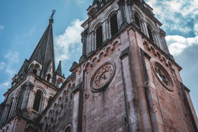 Gothic revival clock towers of Covadonga Basilica under a clear blue sky, showcasing intricate architecture.
