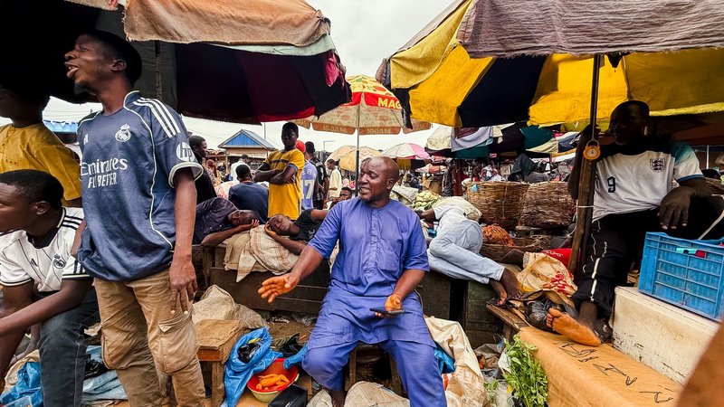 Colorful and lively Nigerian market with street vendors and shoppers captured amidst vibrant umbrellas.