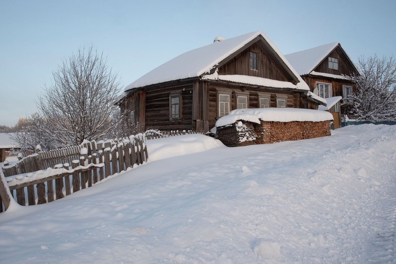 Rustic wooden cabins surrounded by snow and frost on a winter day