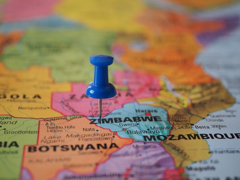 A blue pushpin marks Zimbabwe on a colorful close-up map highlighting its geographical position.