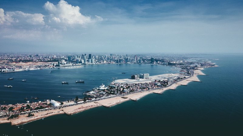 Stunning aerial shot of Luanda's coastline and urban skyline under a blue sky.