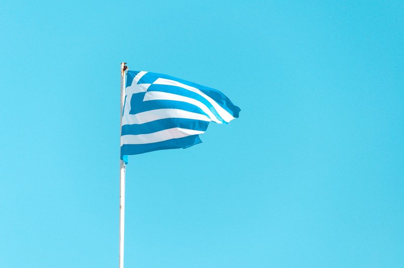 Vibrant Greek flag waving against a clear blue sky in Athens symbolizing national pride.